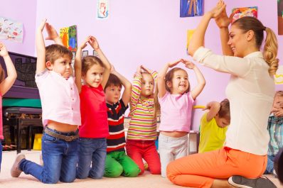 children in nursery copying actions of nursery nurse