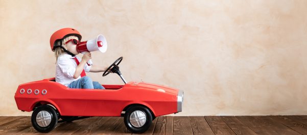 boy in toy car with megaphone