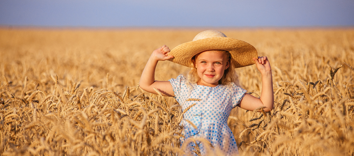 small girl in sunhat playing in wheat field