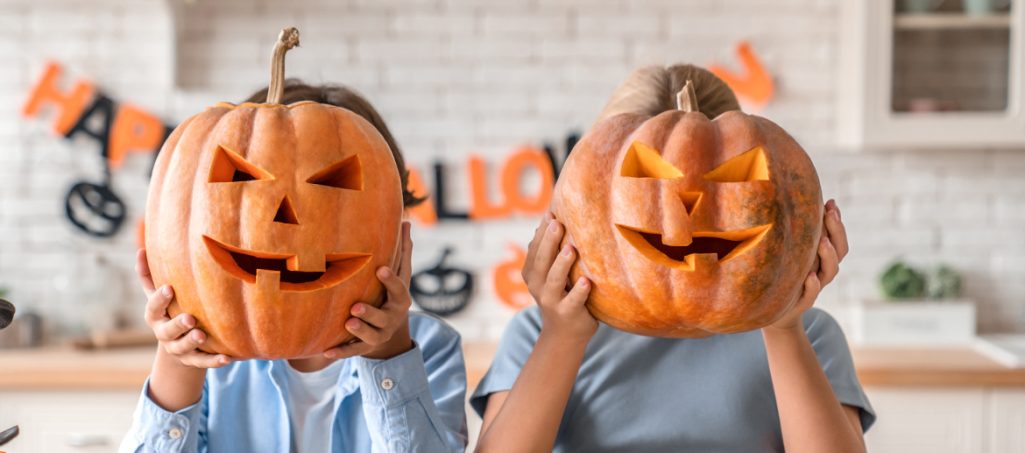 Children holding carved Halloween pumpkins in front of their faces
