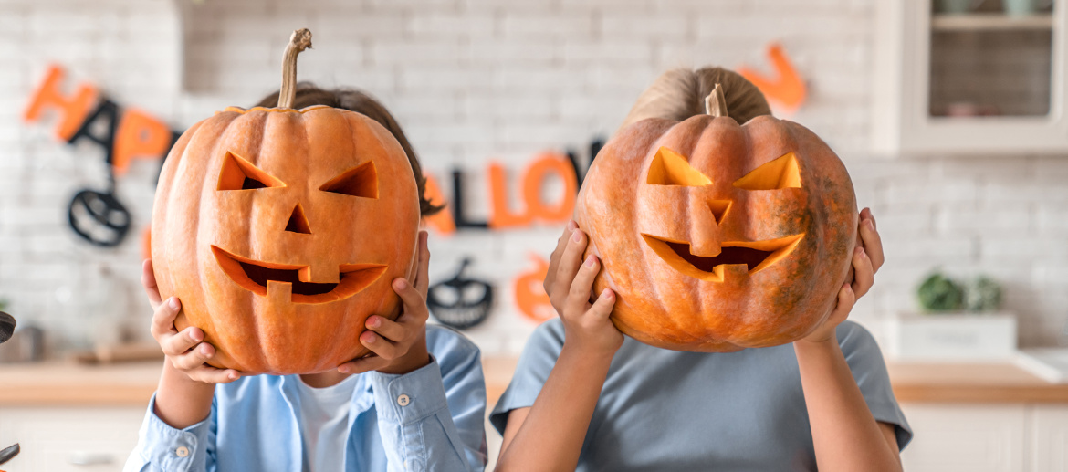 Children holding carved Halloween pumpkins in front of their faces