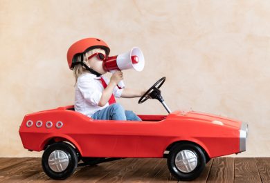 Boy in toy car with megaphone