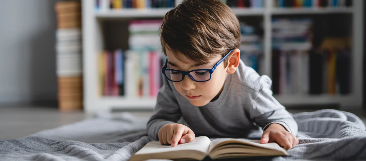 Young boy wearing glasses reading a book